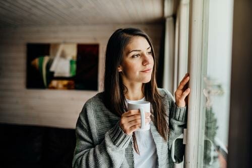 スペインでコーヒーを飲みながら窓の外を眺めている女性。