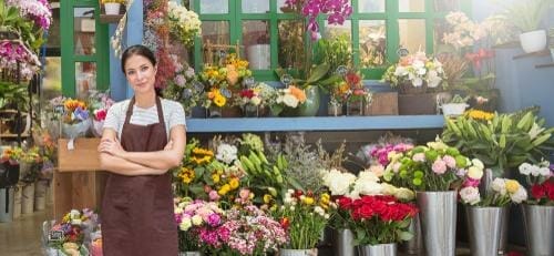 スペインの花屋の前にエプロンを着た女性が立っています。