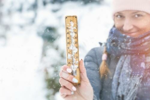 スペインの雪の中で体温計を掲げる女性。