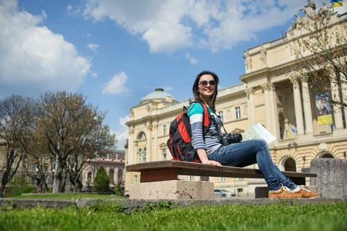 スペインの建物の前のベンチに座っている若い女性。