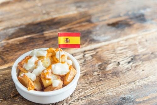 スペインで白いボウルに入ったポテトフライが木のテーブルの上にあります。