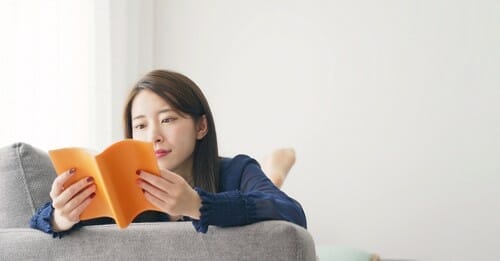 スペインのソファで本を読むアジア人女性。