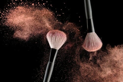 Make-up,Brush,With,Pink,Powder,Explosion,On,Black,Background