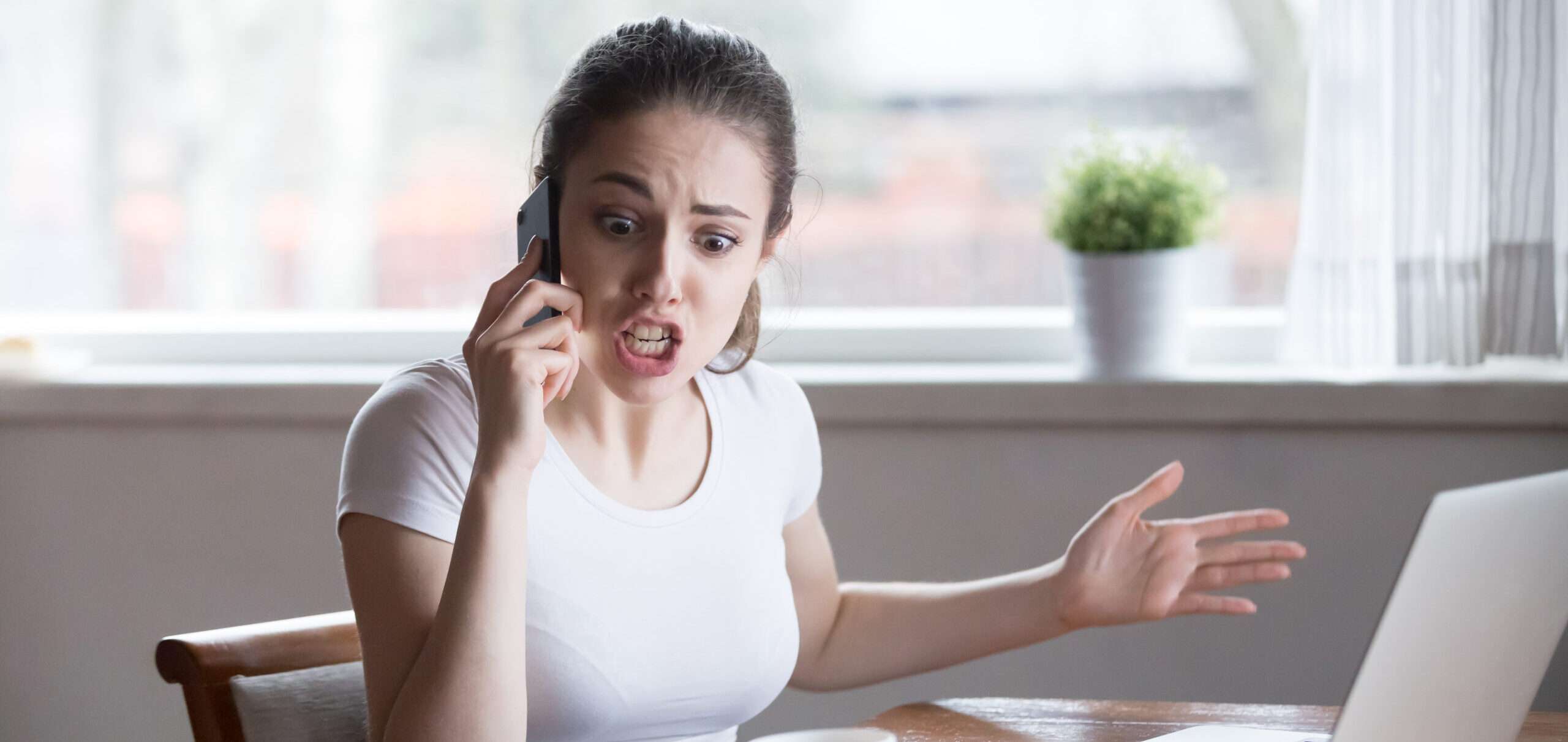電話で話したりラップトップを使用したりしてマルチタスクを行う女性。