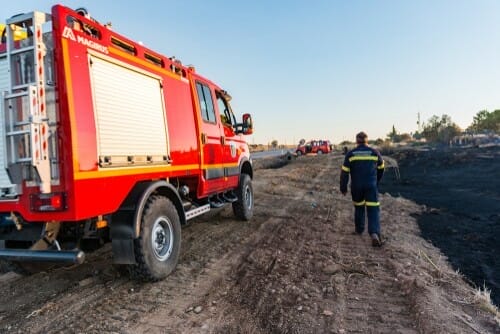 スペインの未舗装の道路で消防士が消防車の隣に立っている。