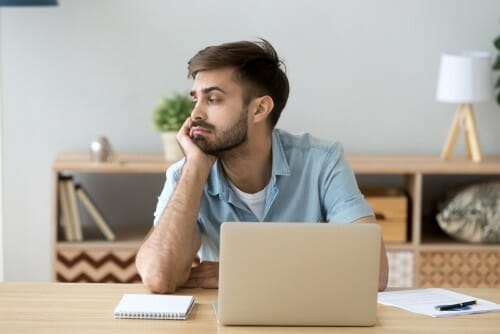 ラップトップを持って机に座り、スペイン語を入力している男性。