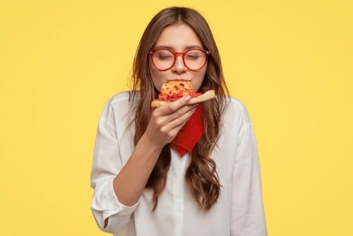 スペインで黄色の背景に女性がピザを食べている。