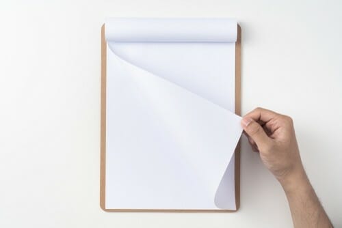 スペインの白い表面にメモ帳を持つ手。