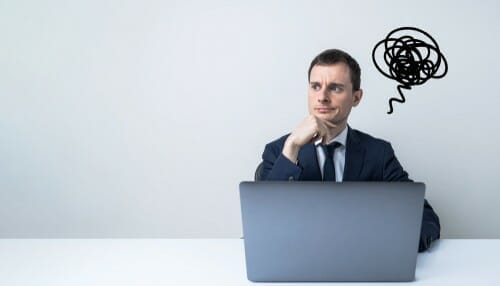 机にノートパソコンを持って座るスーツを着た男性、スペイン