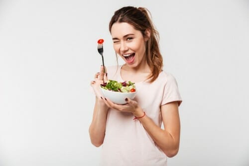 スペインでフォークでサラダのボウルを持つ若い女性。