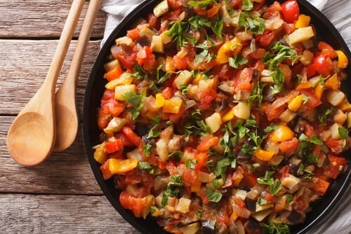 木製テーブルの上に野菜とハーブがたっぷり入ったスペインのフライパン。