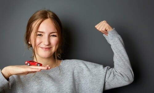 スペインの若い女性がおもちゃの車を持ち、上腕二頭筋を見せています。