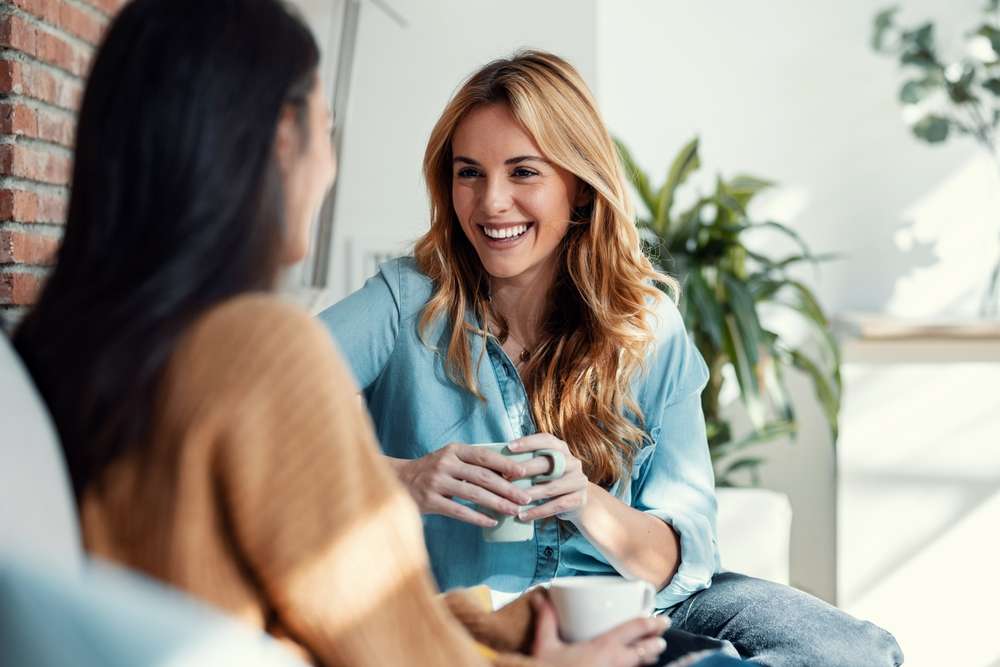 2 人の女性が友好的な会話を交わし、1 人がスペインのマグカップを持っています。