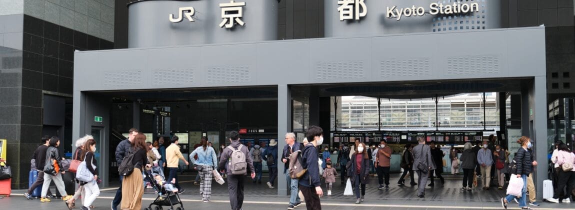 京都駅には人々が出入りしており、入口の上には「JR」と「京都駅」と書かれた看板が掲げられています。近くの居心地の良いカフェでは、京都の活気に満ちた雰囲気を楽しみながら学びたい人向けにマンツーマンスペイン語教室を開催しています。.