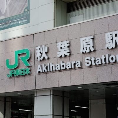 日本の秋葉原の中心部に位置する秋葉原駅の標識には、象徴的な JR のロゴが日本語と英語の両方のテキストで表示されています。.