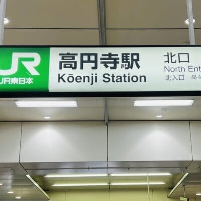 高円寺駅北口の標識。日本語、英語、韓国語の文字が書かれており、高円寺の活気ある多文化シーンを表現しています。.